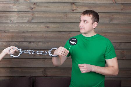 Young handcuffed man holding funny icon on a stickの写真素材