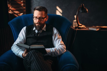 Bearded writer in glasses reads handwritten textの写真素材