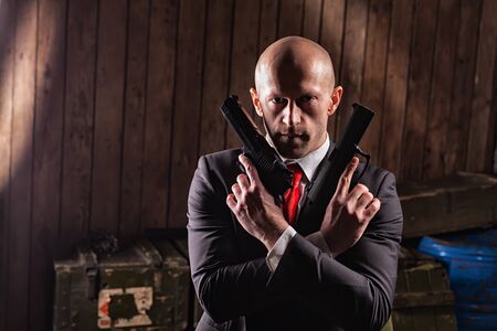 Bald contract killer in suit with two pistolsの写真素材