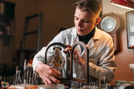 Watchmaker holding old table clockの写真素材