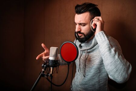 Male singer recording a song in music studioの写真素材