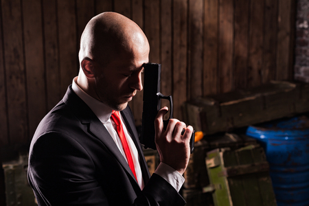 Contract assassin in suit and red tie holds gunの写真素材
