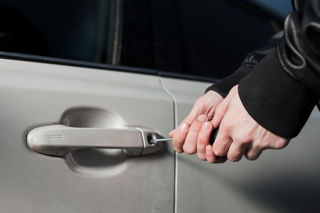Male thief hands open car door with screwdriverの写真素材