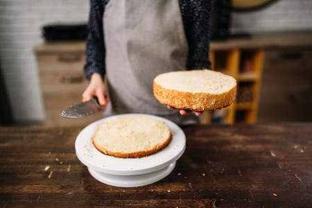 Woman cook hands holds piece of cake and knifeの写真素材