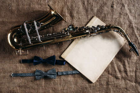 Saxophone, notes and bowtie on canvas backgroundの写真素材