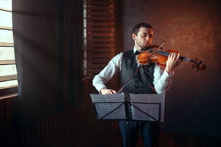 Male violinist playing classical music on violinの写真素材