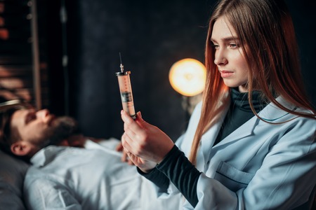 Female doctor with syringe against male patientの写真素材