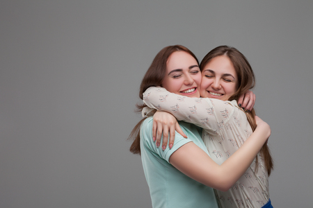 Two happy girlfriends hugs togetherの写真素材