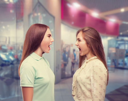 Two girls screams at each other in shopping centerの写真素材