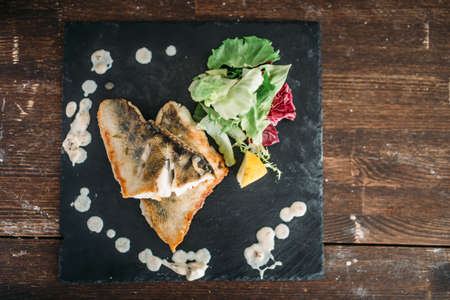 Dish of fried fish decorated with vegetablesの写真素材