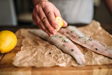 Chef hands squeeze lemon on raw fish closeup viewの写真素材