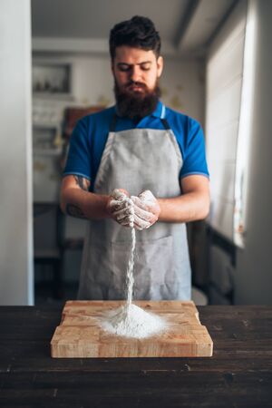 Chef with flour in hands working on cutting boardの写真素材