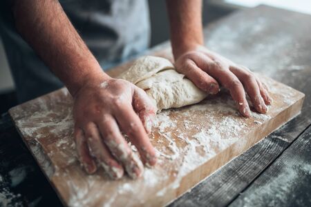 Baker hands kneading the dough with flourの写真素材
