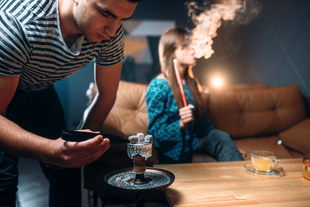 Young couple leisure at night club, smoking hookah