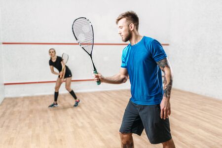 Active couple with rackets play squash gameの写真素材