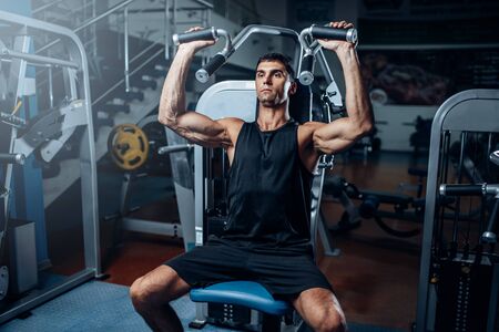 Tanned man training on exercise machine