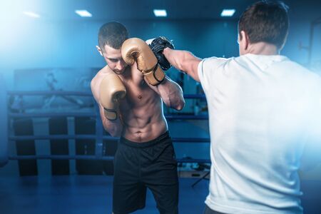 Boxer in gloves exercises with sparring partnerの写真素材