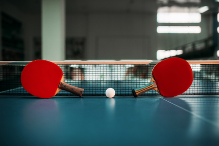 Two tennis rackets and ball against net on tableの写真素材