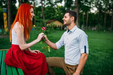 Young man gives flower to woman, romantic meetingの写真素材