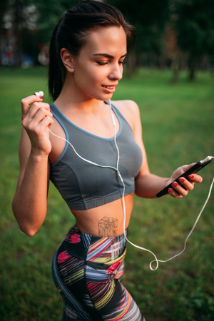 Woman in headphones sitting on grass and relaxの写真素材