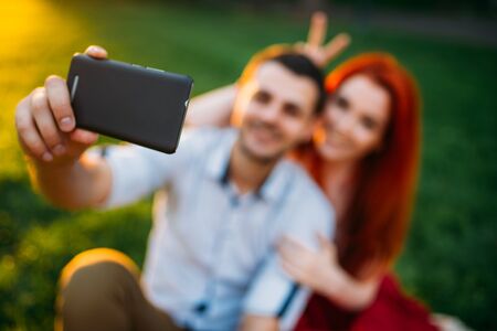 Love couple makes selfie in summer park on sunset