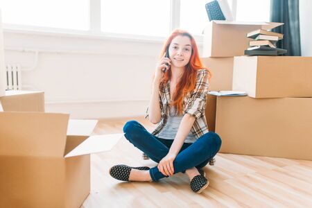 Woman among cardboard boxes talking by phone