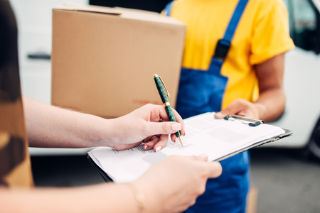 Male worker in uniform gives parcel to the clientの写真素材