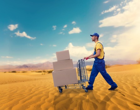 Courier with trolley in desert, cargo deliveryの写真素材