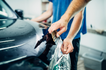 Worker hands wraps car hood in protective coatingの写真素材