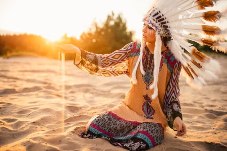 Woman in suit of American Indian on sunset