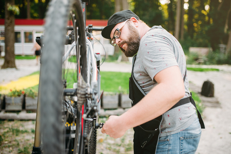 Repairman works with bike wheel, cycle workshopの写真素材