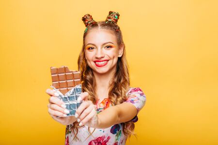 Woman with playful look bites huge chocolateの写真素材