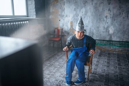Strange man in aluminum foil helmet watch TV, UFOの写真素材