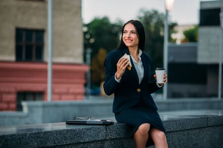 Happy business woman with sandwich and coffeeの写真素材