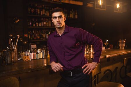 Young man in shirt standing at the bar counterの写真素材