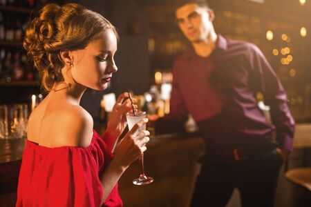 Woman in red dress with cocktail in hand, flirtingの写真素材