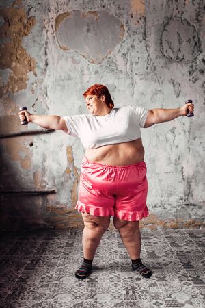 Fat woman on workout with dumbbells, obesityの写真素材