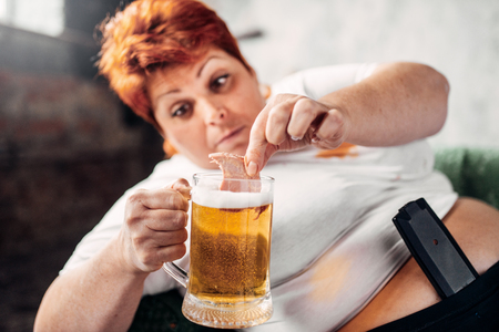 Overweight woman drinks beer, obesityの写真素材