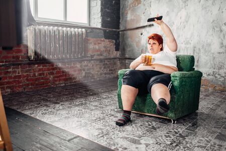 Overweight woman watches TV, bulimic, fattyの写真素材