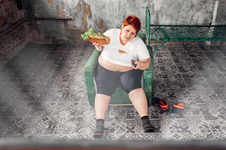 Overweight woman watches TV, bulimic, fattyの写真素材