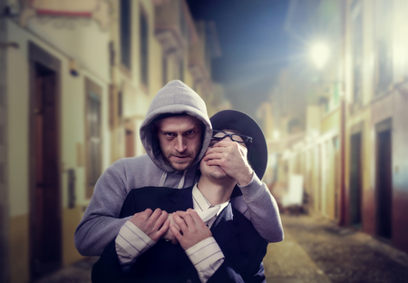 Thief with knife attack his victim on night streetの写真素材