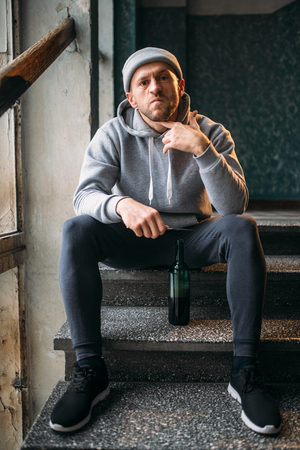 Male robber with knife sitting on the stairsの写真素材