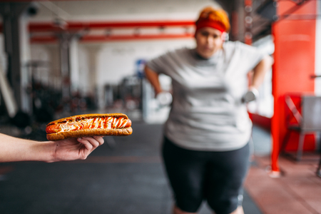Trainer with hotdog forces fat woman to exerciseの写真素材