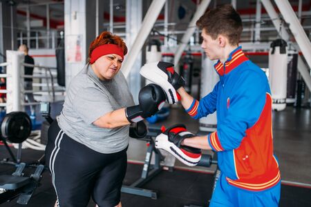 Fat woman makes selfie with instructor in gymの写真素材