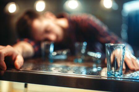 Drunk man sleeps at bar counter, alcohol addictionの写真素材