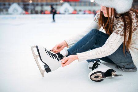 Young woman ties the shoelaces on skatesの写真素材