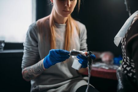 Female tattooist prepares tattoo machineの写真素材