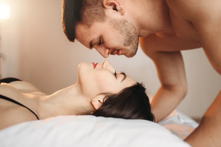 Love couple lies on big white bed, sex romance
