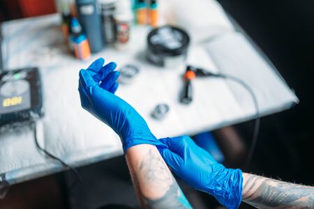 Female tattoo artist hands in blue sterile glovesの写真素材
