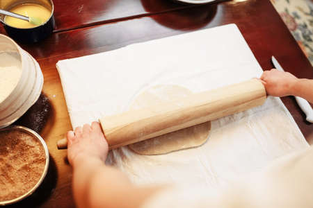 Chef roll out the dough with rolling pin, top view